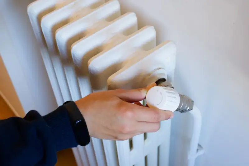 Ajustando el termostato de un radiador para optimizar la calefacción central en comunidades de vecinos.